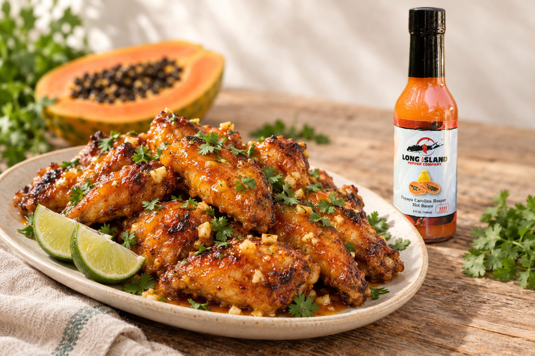 Chicken wings in papaya garlic butter sauce, with a bottle of Papaya Carolina Reaper hot sauce behind